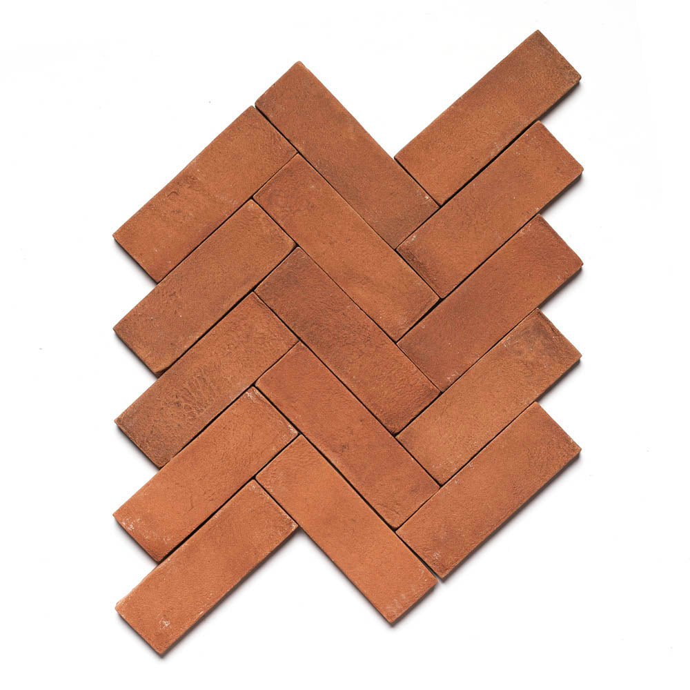 Zia Tiles 2x6 Rectangle + Red Clay tiles are arranged in a herringbone pattern on white, creating an interlocking, diagonal design inspired by San Miguel de Allende architecture.