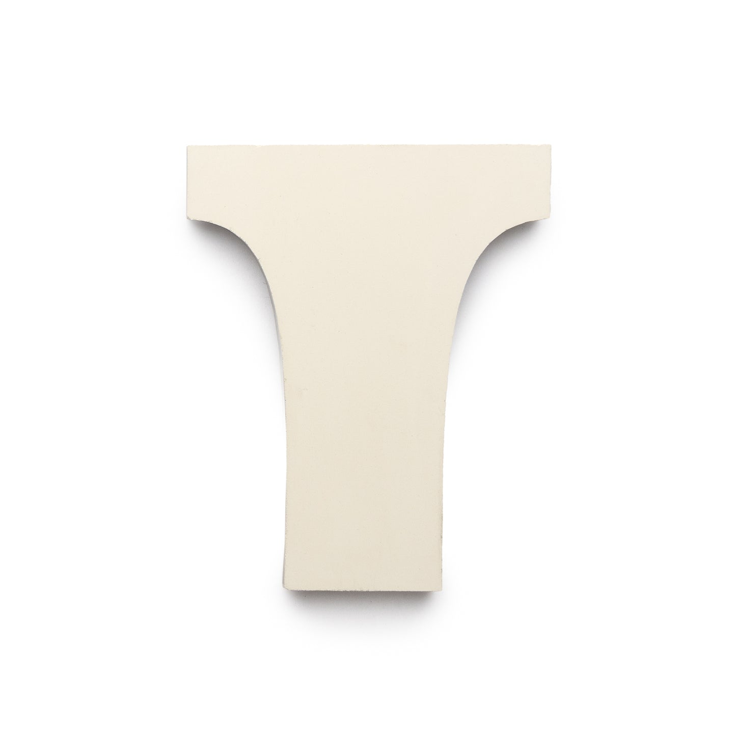 A flat, off-white tile shaped like an uppercase T with rounded inner corners, the Arco Bone + Black + Mustard by Zia Tile evokes a handmade Moroccan style and is set against a white background.