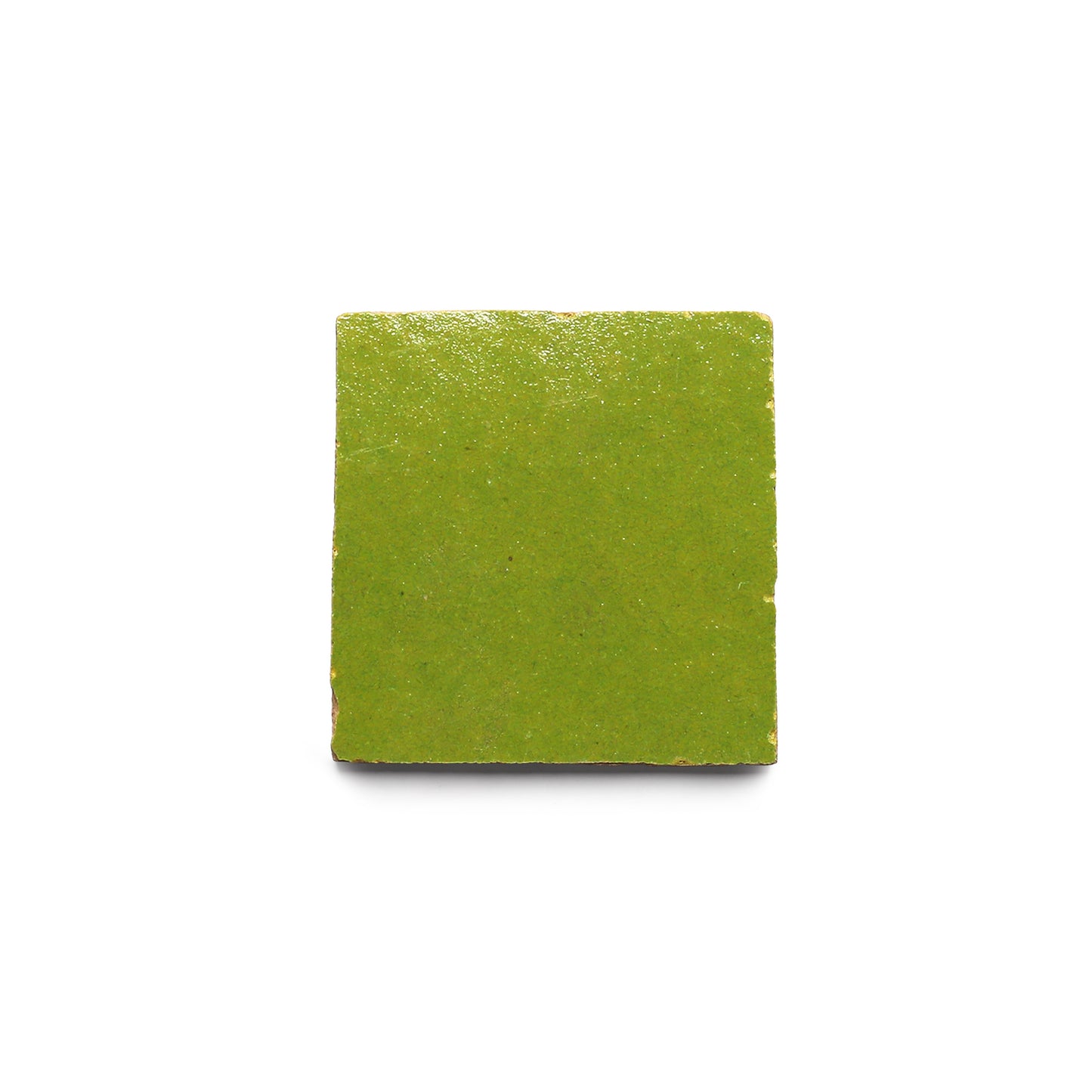 A single Avocado 2x2 zellige tile by Zia Tile, square and green with a glossy finish and slightly rough edges, centered on white, showcases the artisanal charm of Moroccan craftsmanship.