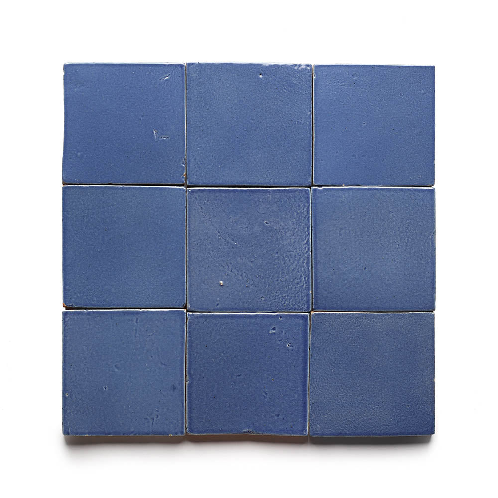 Nine matte blue Azul 4x4 sample tiles by Zia Tile are arranged in a 3x3 grid on a white background. Each handmade cement tile features unique texture and edges, exemplifying Zia Tiles signature craftsmanship.