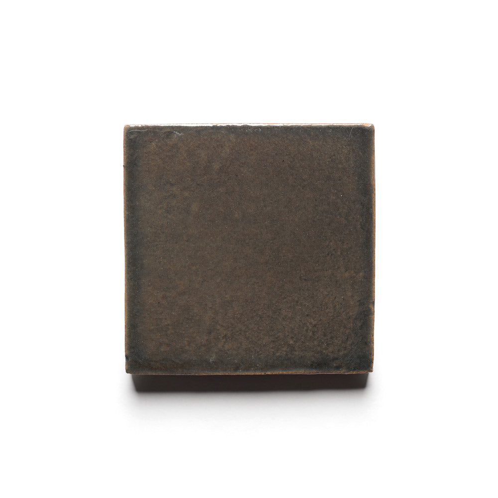 The Zia Tile Cacao 4x4 is a single square tile in dark brown with a subtly textured surface, inspired by traditional ceramics, shown against a plain white background.