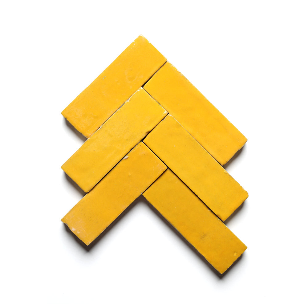 Six Cadmium 2x6 zellige tiles by Zia Tile, shown in a chevron pattern on a white background, add bold Moroccan flair to your kitchen backsplash.