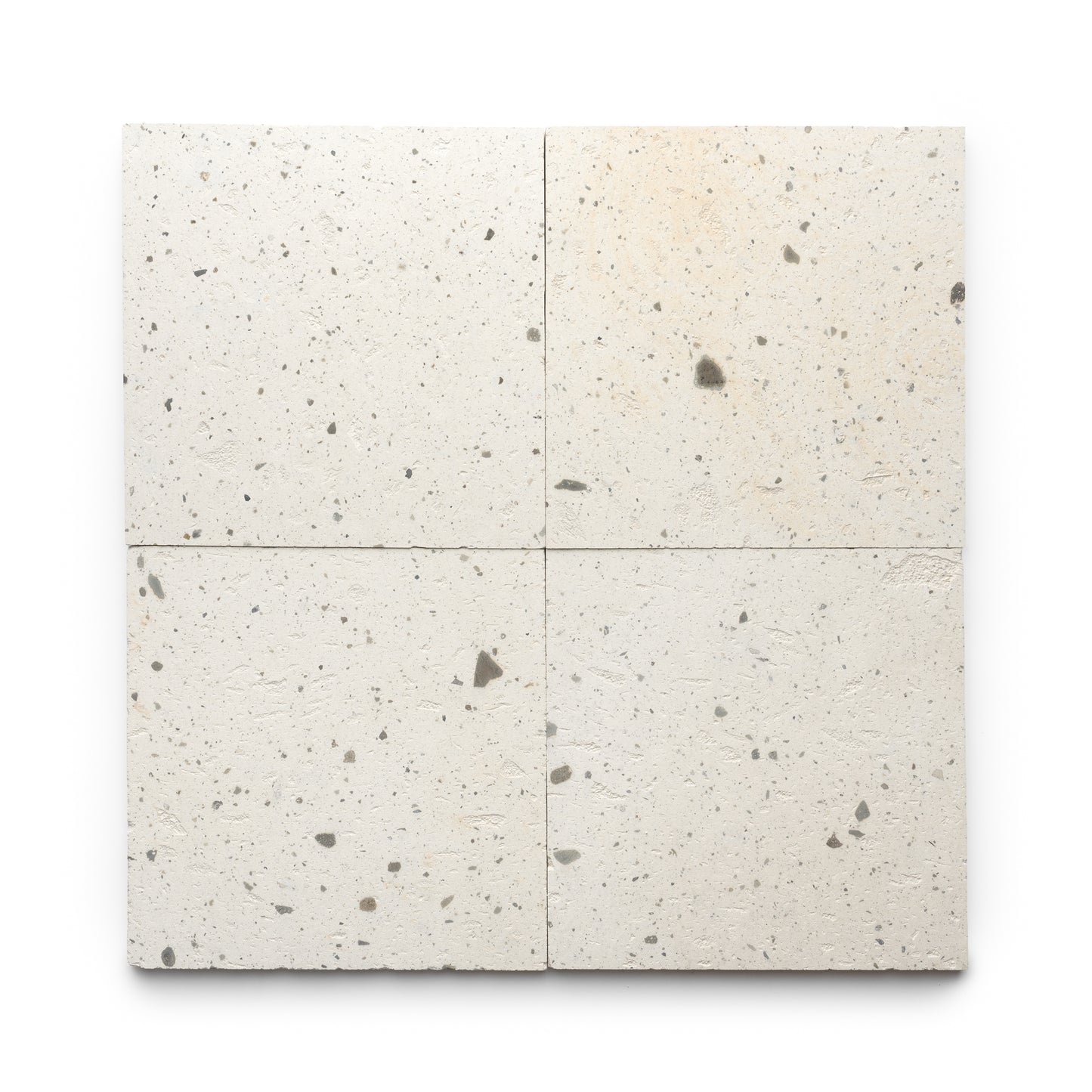 Four Caldera 12x12 tiles by Zia Tile, off-white with a rough speckled texture and small gray spots, are arranged in a 2x2 grid on a white background.