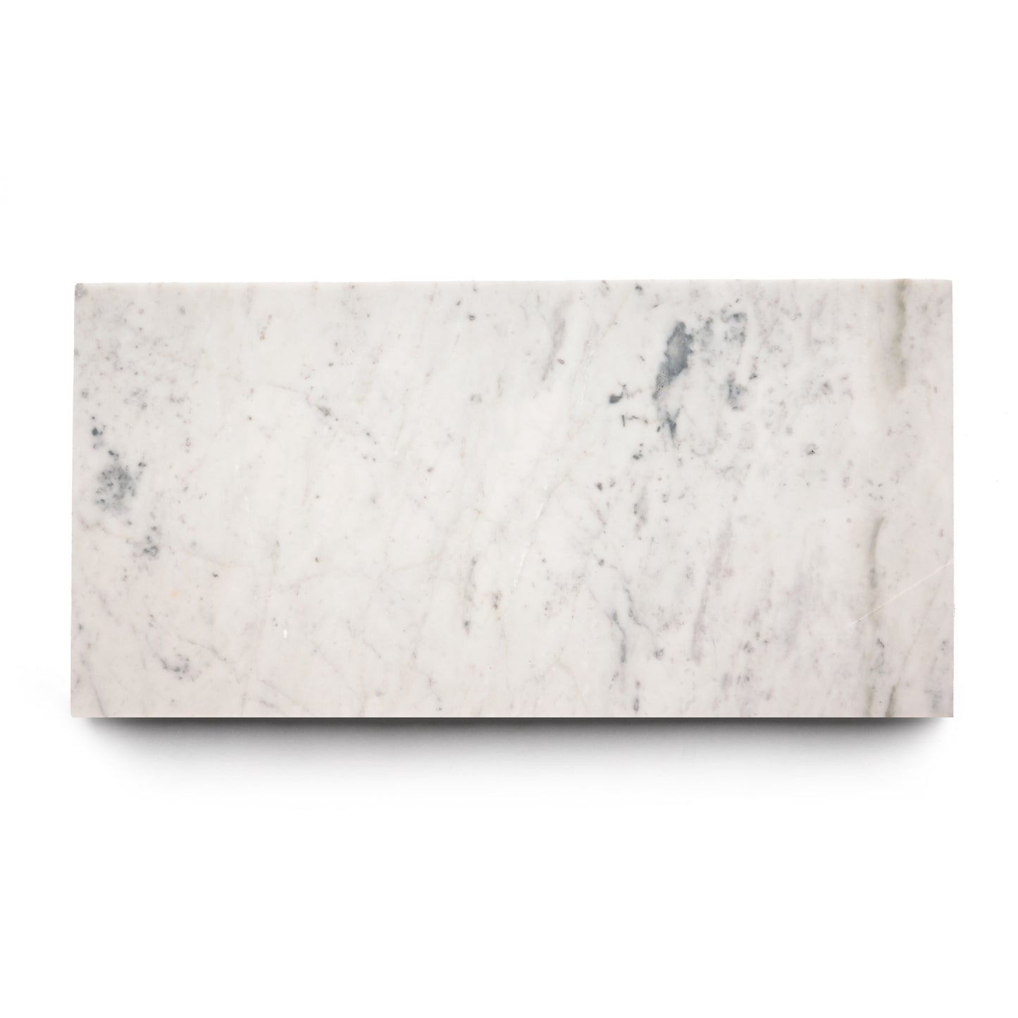 The Carrara 12x24 by Zia Tile is a rectangular white marble slab with subtle gray veining, echoing the look of handmade tile, shown against a plain white background.