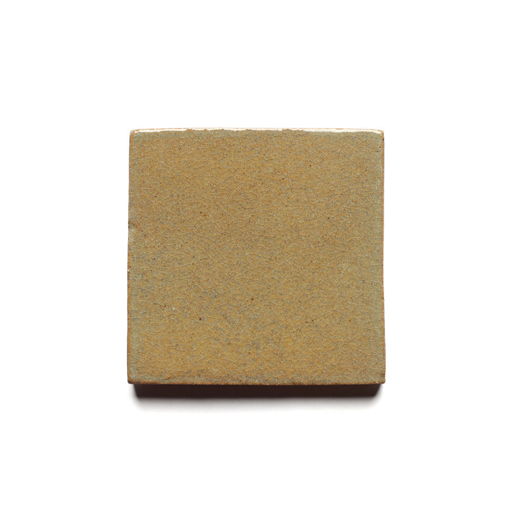 The Creosote 4x4 by Zia Tile is a handmade, rectangular, tan tile with a slightly textured surface, inspired by ceramic arts and displayed on a plain white background.