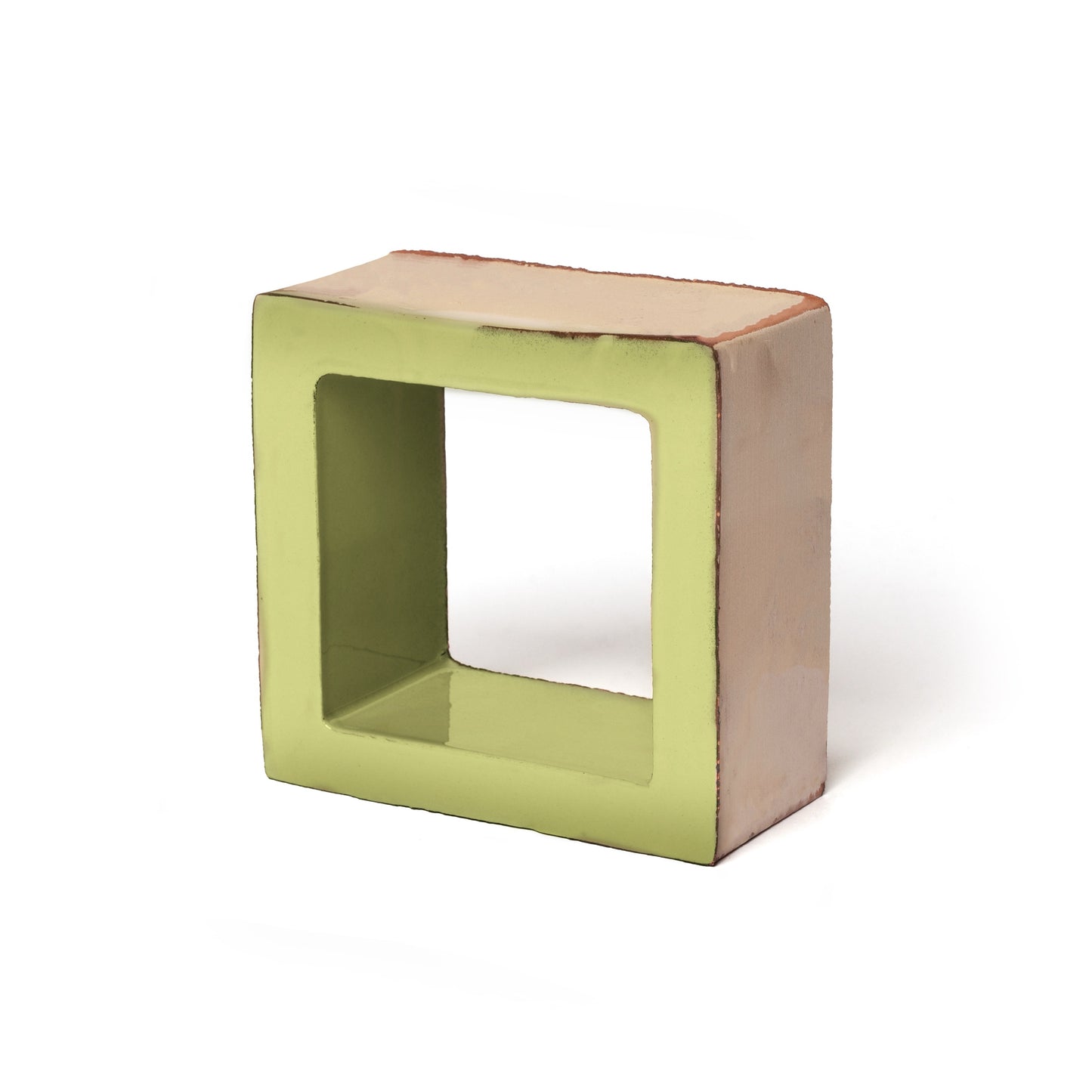 The Cube + Aurora Green by Zia Tile is a ceramic sculpture with a square, hollow form reminiscent of a Terra Forms tile—its front glazed in light green and other sides in beige, shown against a white background.