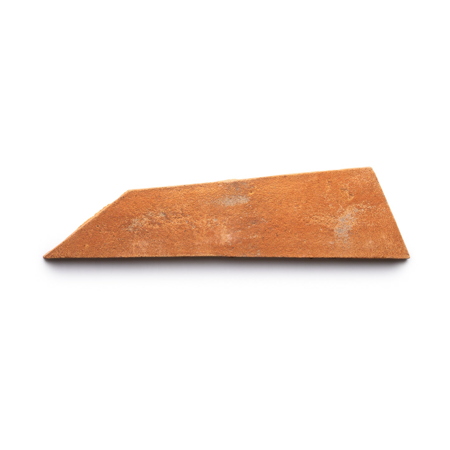 The Tornillo + Fired Earth tile by Zia Tile is a single, irregularly shaped shard of reddish-brown terracotta pottery, displayed on a white background.