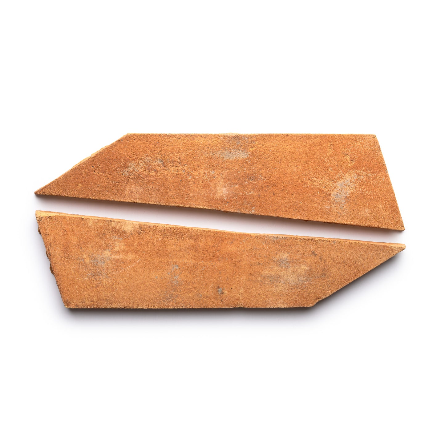 Two irregular, rust-colored Tornillo + Fired Earth terracotta shards by Zia Tile, with angled edges and placed parallel on a white background, resembling two fragments of a broken tile.
