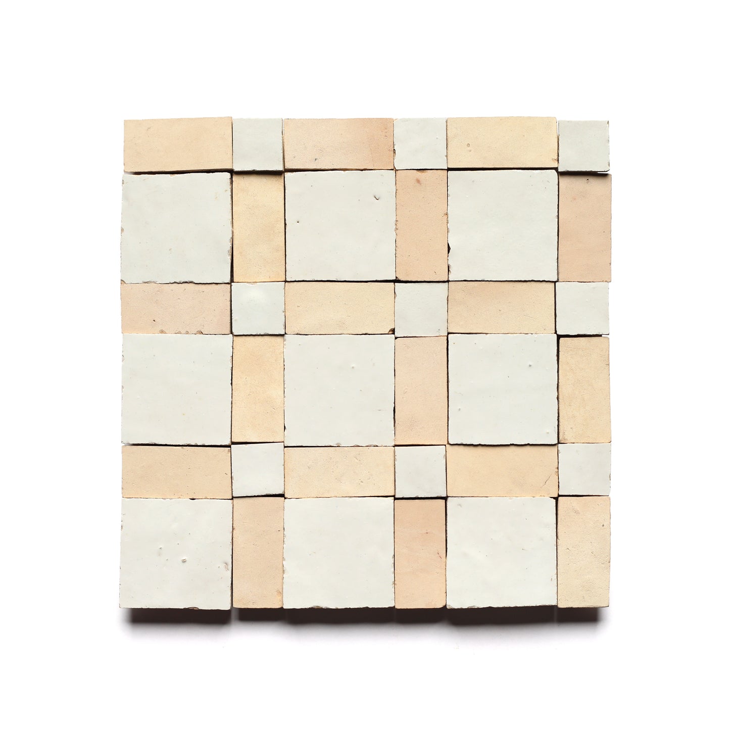Gambit 2 by Zia Tile is a square mosaic inspired by Moroccan tile, featuring a matte cream and beige checkerboard in alternating large and small squares—perfect for a stylish kitchen backsplash with a white backdrop.