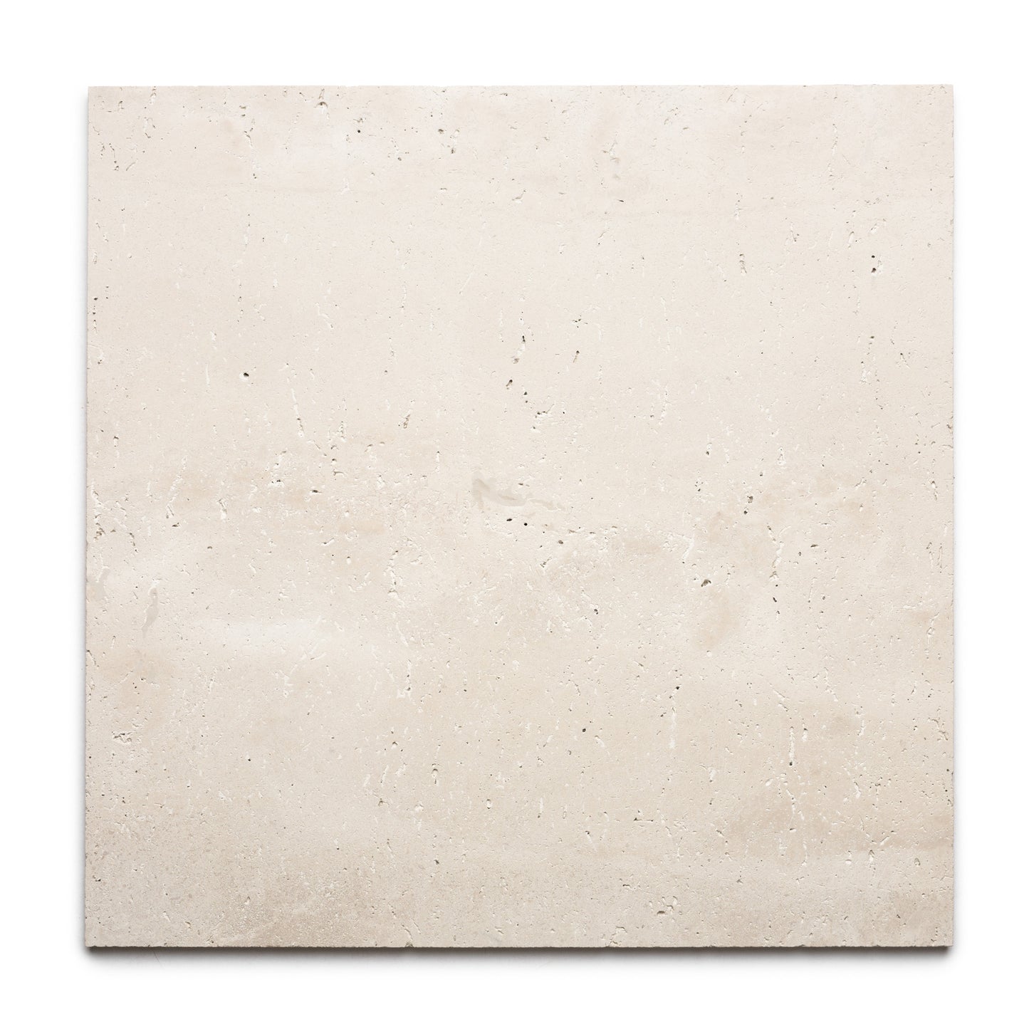 The Mesa 24x24 by Zia Tile is a rectangular slab of light beige Mexican Cantera stone tile with a smooth surface, subtle natural texture, small holes, and faint mineral patterns, displayed against a white background.