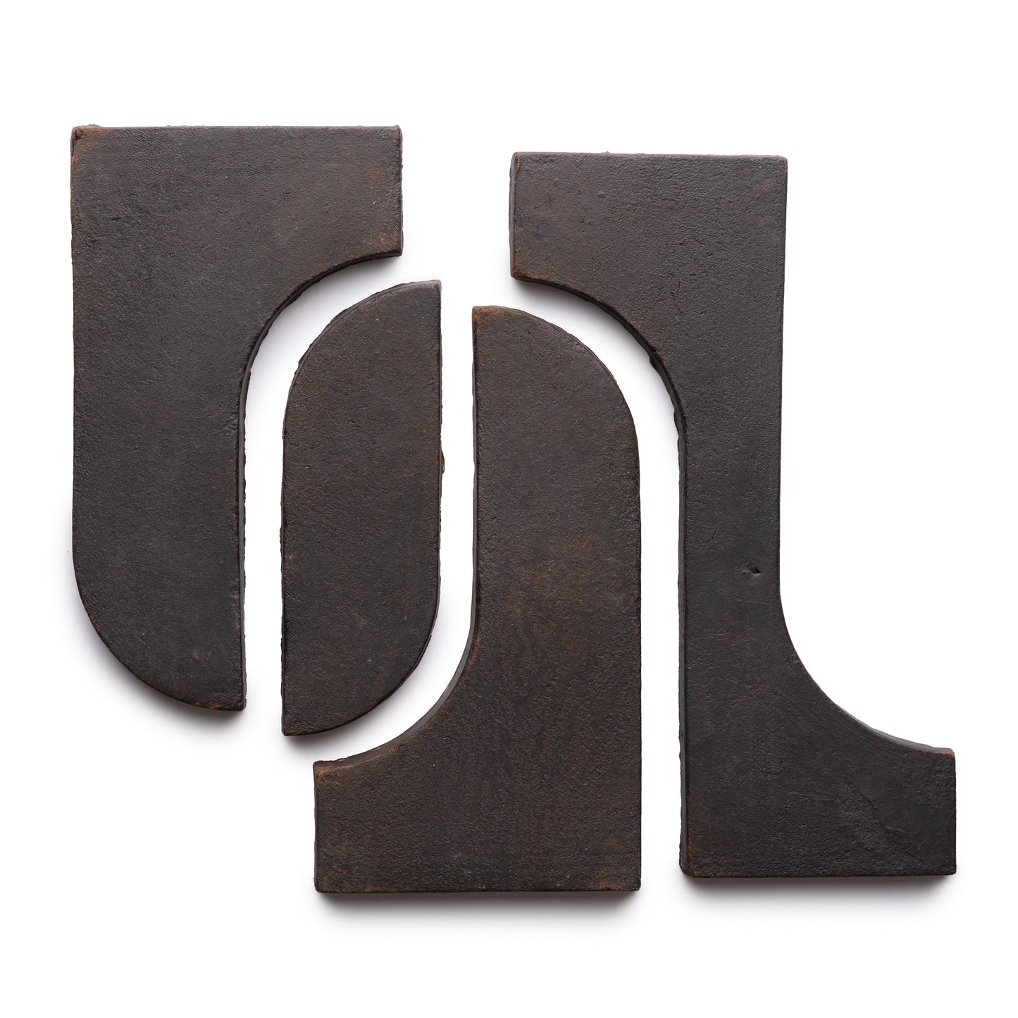 Four Durango + Oscura ceramic tiles by Zia Tile are arranged on a white background, forming an abstract pattern with curved and straight edges facing each other.