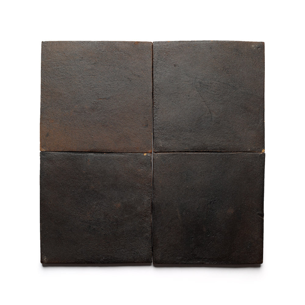 Four 8x8 Square + Oscura tiles by Zia Tile, featuring a dark brown tone, subtle color variation, and uneven edges, are arranged in a 2x2 grid. These handmade terra cotta tiles are inspired by San Miguel de Allende.
