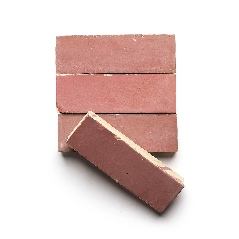 Four rectangular Pietro Pink 2x6 tiles are neatly stacked on a white background, with one tile leaning diagonally—perfect for adding a Moroccan-inspired touch to your kitchen backsplash.