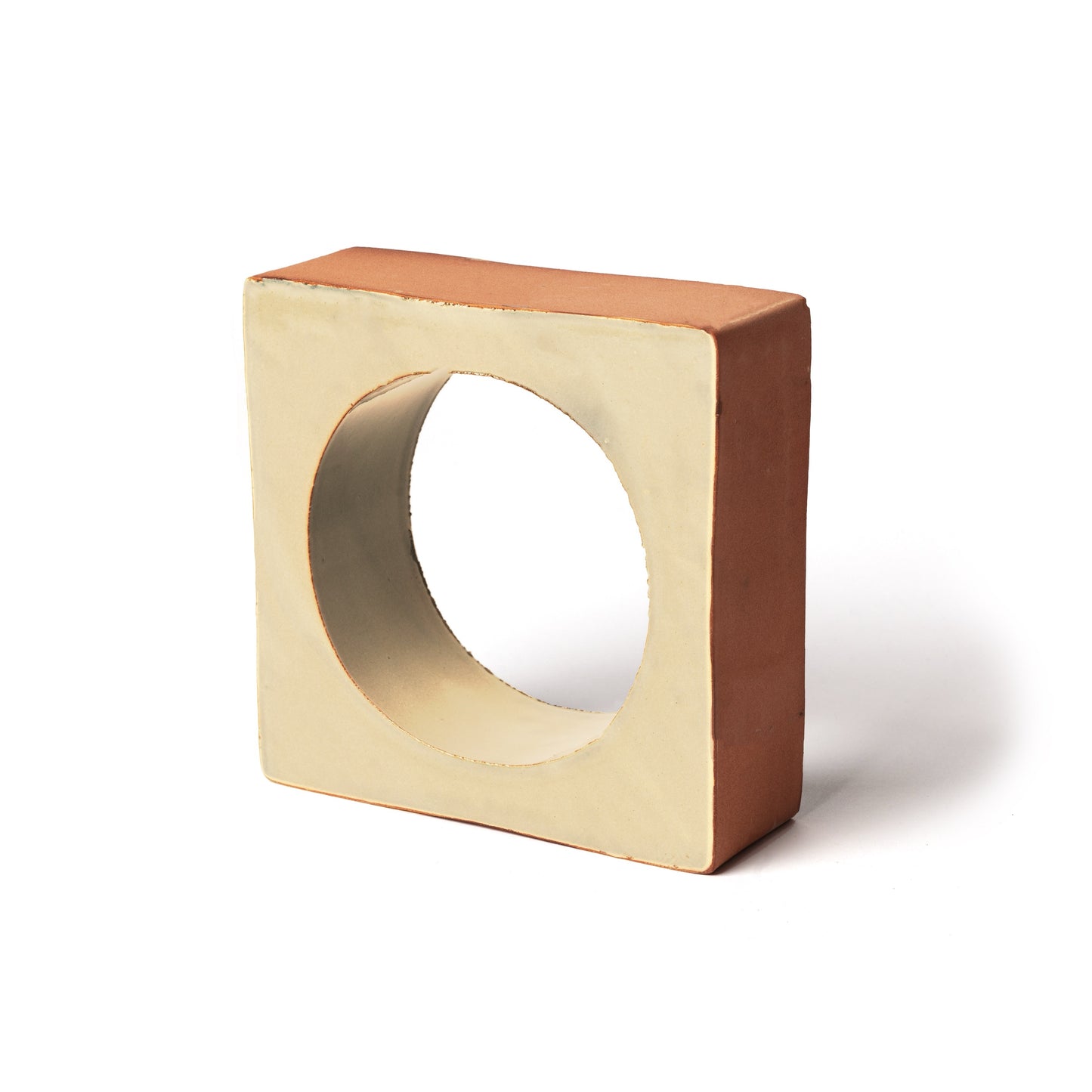 The Portal + Titan by Zia Tile is a square, two-toned ceramic 3D tile with a central circular hole. Its light beige front contrasts with terra cotta sides and top, and it stands upright against a white background.