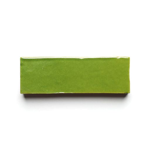 The Prairie Green 2x6 tile is a rectangular, glossy Moroccan zellige displayed on a white background, featuring smooth edges and a shiny surface that reflects light beautifully.