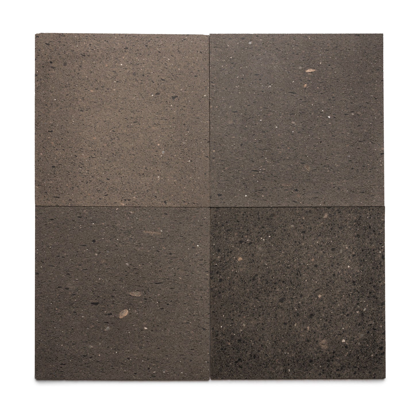 Four Volcan 24x24 tiles by Zia Tile, dark gray Mexican Cantera stone with subtle speckles and color variation, displayed in a 2x2 grid on a white background.