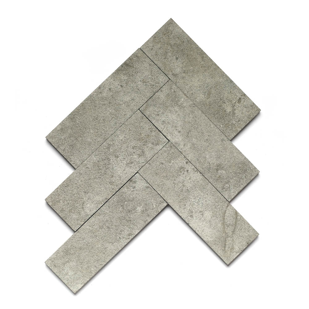 Five rectangular gray Basilica 4x12 + Bush Hammered tiles by Zia Tile are arranged in a herringbone pattern on a white background, showcasing timeless elegance reminiscent of Moroccan limestone.