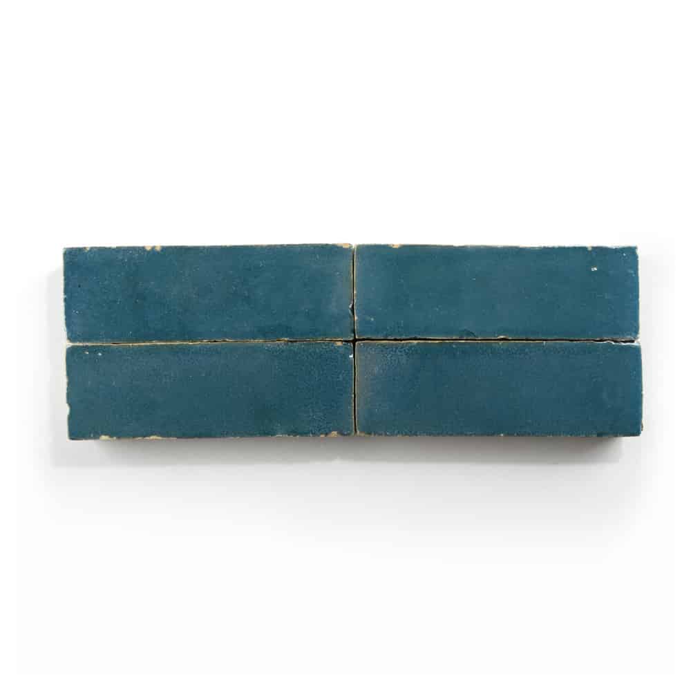 Four rectangular blue Aegean 2x6 Zia Tile cement tiles are arranged in two rows of two on a white background, with slight wear visible along the edges.