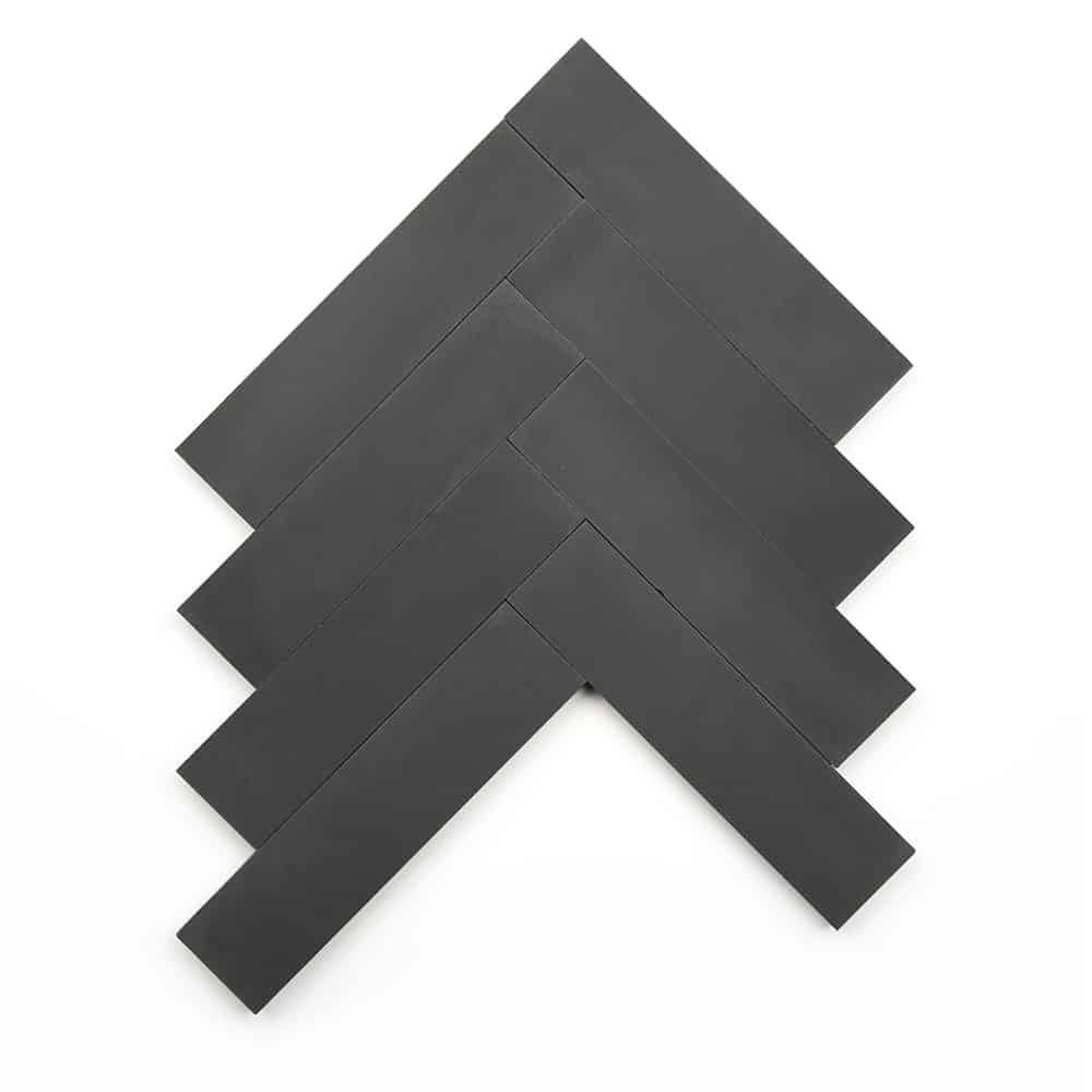 Five rectangular Ash 2x8 tiles from Zia Tile are arranged in a black herringbone pattern on a white background, forming a zigzag or upward-pointing arrow shape.