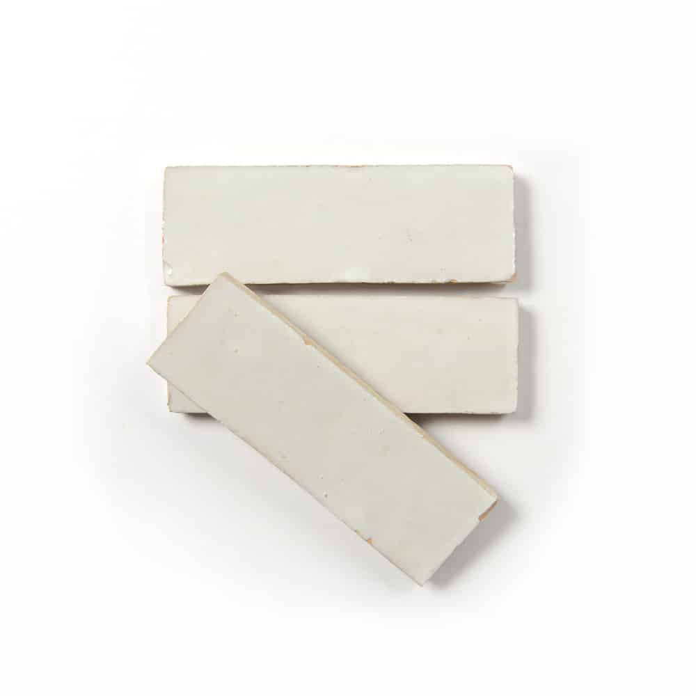 Three Casablanca 2x6 sample tiles by Zia Tile, featuring a handmade look, are arranged on a white background—two placed horizontally and one diagonally overlapping them.