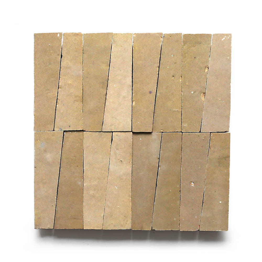 Twelve Glazed Earth Trapezoid samples by Zia Tile are arranged in a 3x4 grid. Each tan tile is slightly angled, forming an uneven geometric pattern on a white background.
