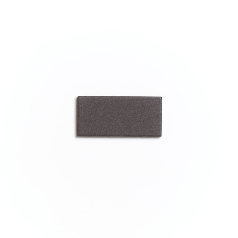 The Ironwood 2x4 ceramic tile by Zia Tile, small, rectangular, and flat with a dark gray matte finish, is centered on a plain white background.