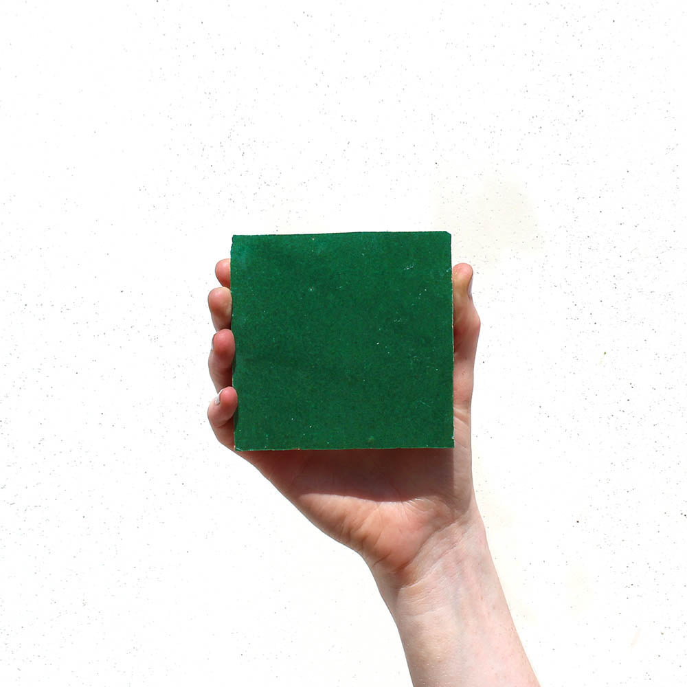 A hand holds up a large, square Jade 4x4 tile against a plain white background.