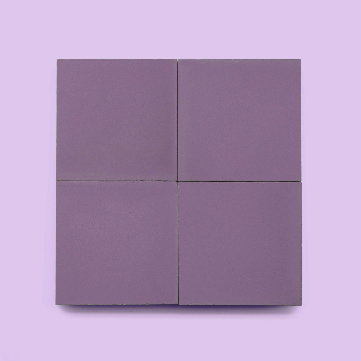 Four matte lavender Montana 4x4 tiles are arranged in a 2x2 grid on a light purple background. Ideal for kitchen backsplashes or bathroom walls, the tiles are evenly aligned with narrow gaps between them.