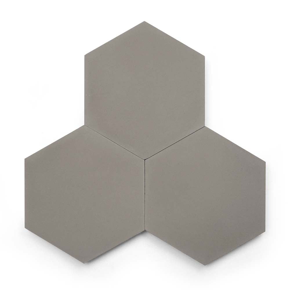 Three Pewter Hex tiles in gray are arranged with two at the bottom and one centered above, resembling a honeycomb cluster against a white background and highlighting the modern style of these cement tiles.