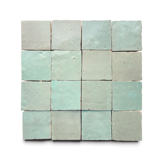 A grid of sixteen Absinthe 2x2 tiles, square and pale turquoise with subtly uneven surfaces and edges, arranged in four rows and four columns on a white background channels classic Moroccan tile artistry.