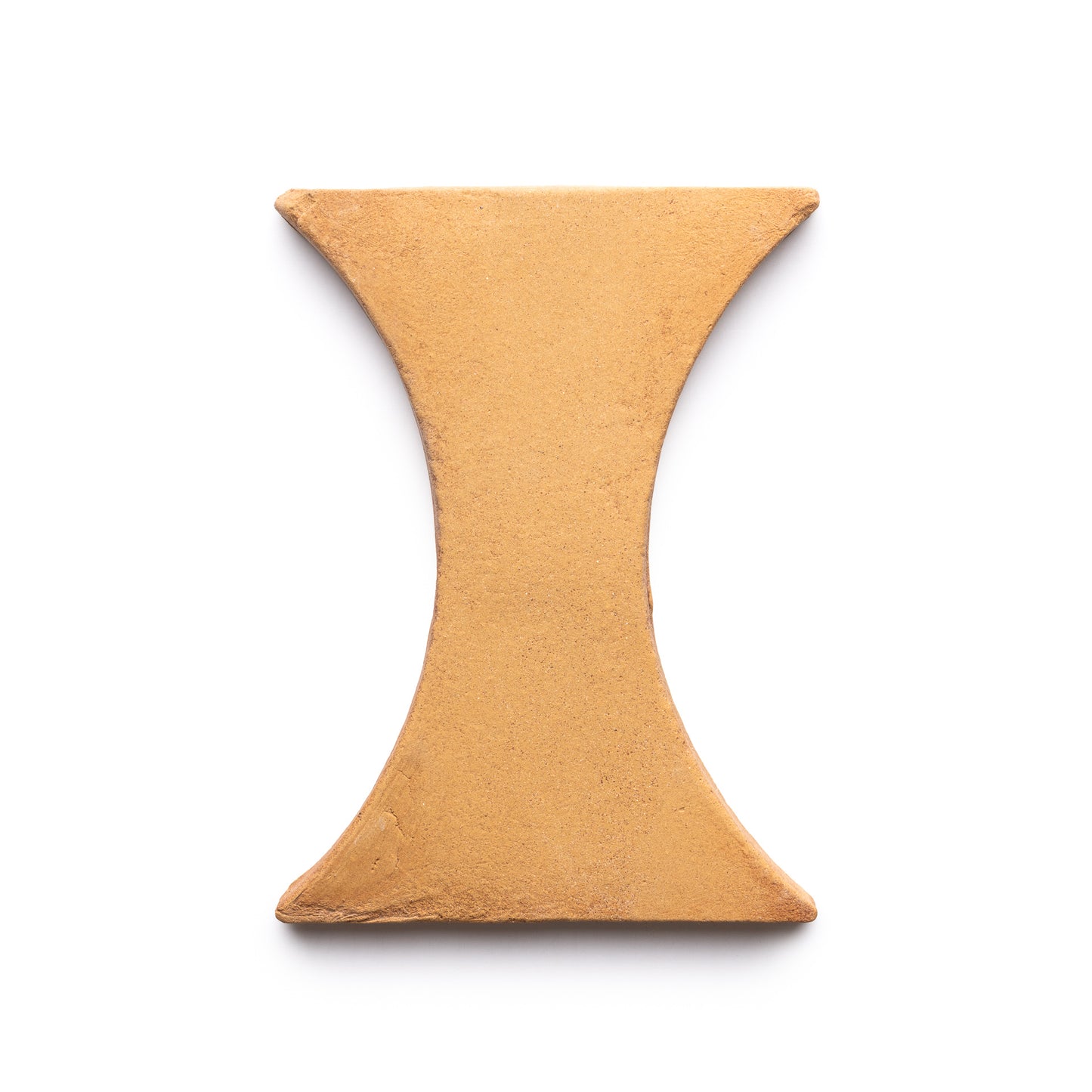 The Oaxaca + Adobe tile by Zia Tile is a tan, hourglass-shaped ceramic tile with smooth surfaces and subtly rounded edges, shown on a white background.