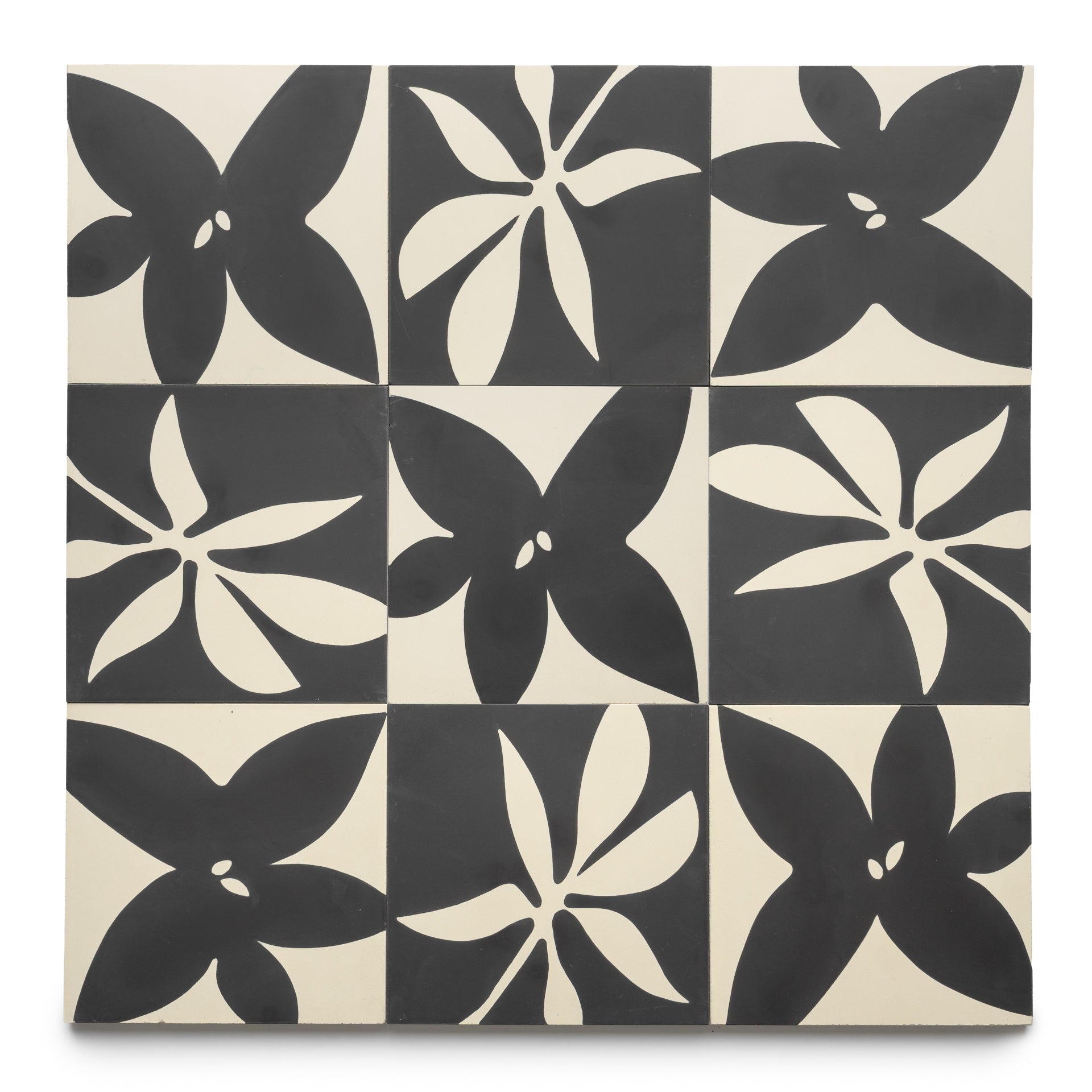 The Flora 8x8 Set Black + Bone by Zia Tile features nine square tiles in a grid, each with bold five-petal black and white floral patterns on alternating backgrounds for a striking geometric style.