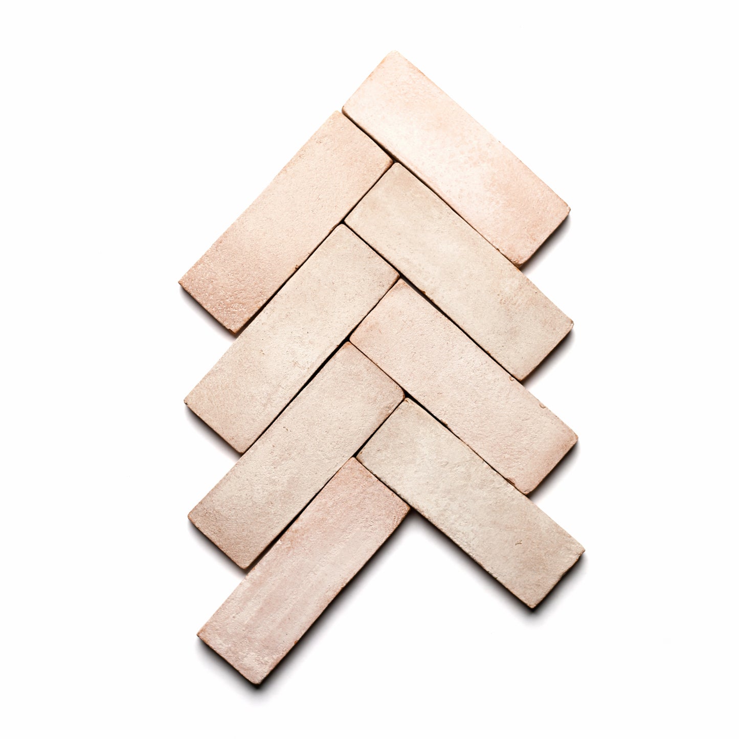 Five 2x6 Rectangle + Blanco bricks by Zia Tile are arranged in a diagonal herringbone pattern on a white background, creating a chevron-like, textured design inspired by ceramic arts.