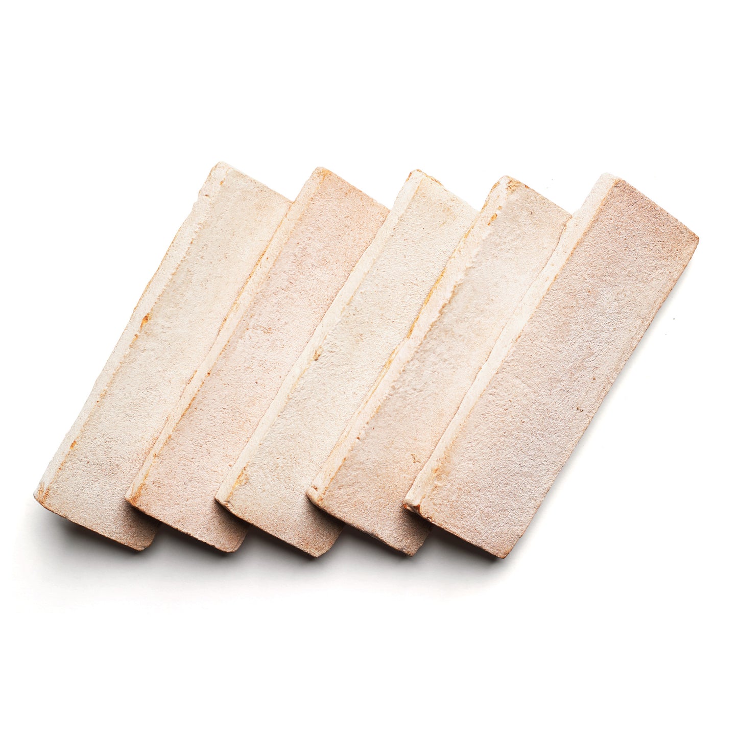 Five 2x6 Rectangle + Blanco tiles by Zia Tile, arranged in a slightly fanned-out row on a white background, showcase handmade character and warm hues inspired by ceramic arts.