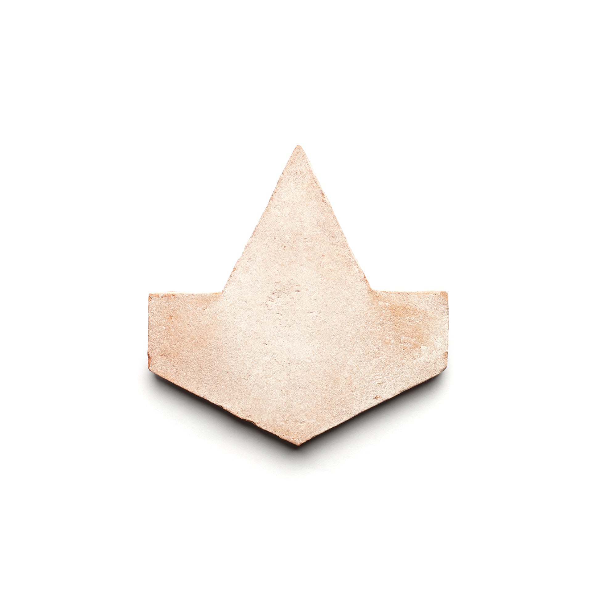 Alcazar + Blanco by Zia Tile: a light beige, arrowhead-shaped ceramic tile with a textured surface, inspired by handmade Cotto and classic ceramic arts, displayed on a white background.