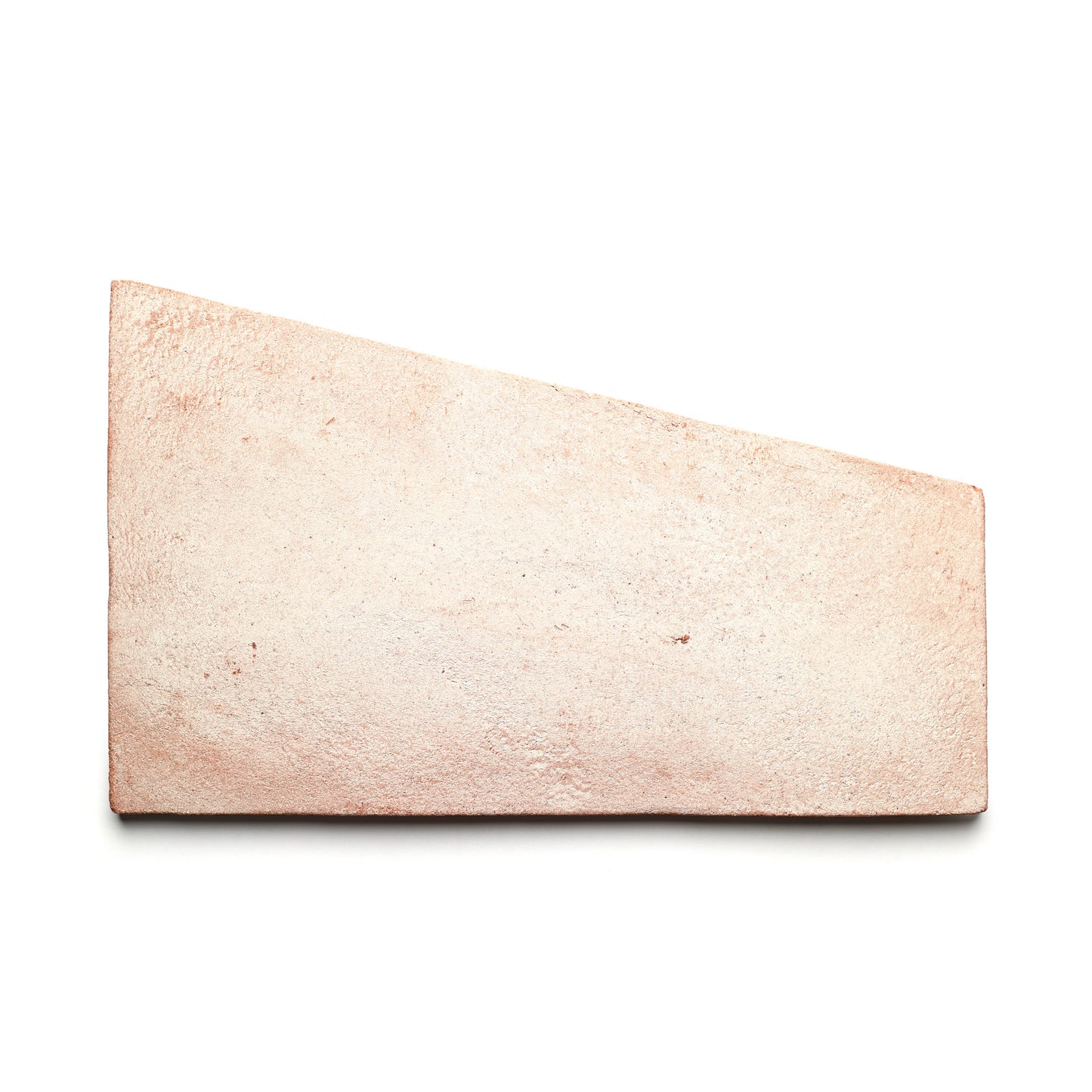 A single Toltec + Blanco handmade Cotto brick by Zia Tile, in a light pinkish-brown trapezoidal shape, rests on a white background.