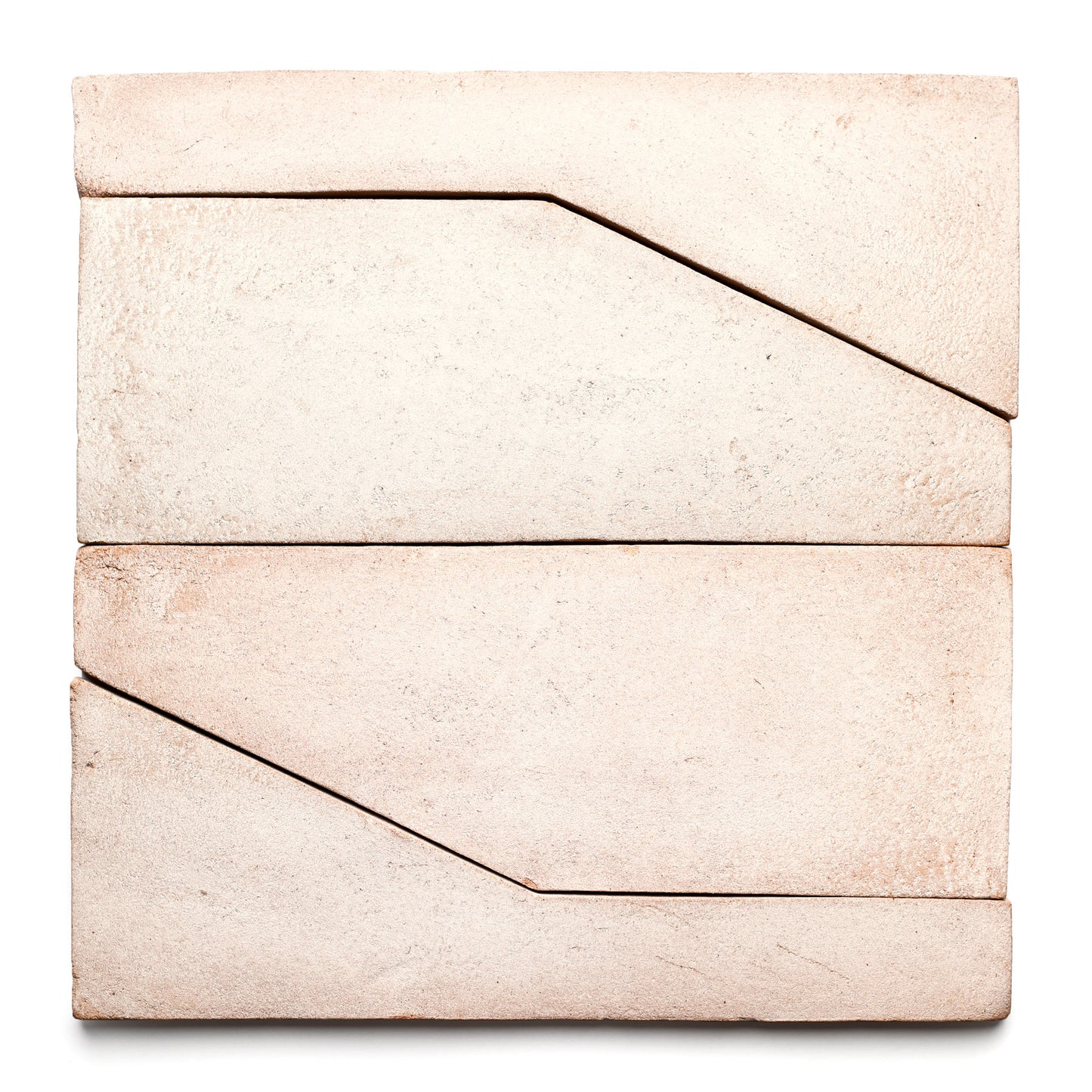 Four Zia Tile "Zocalo + Blanco" rectangular cream tiles are arranged in a square, each featuring a diagonal groove that forms geometric patterns where they meet, all set against a white background.