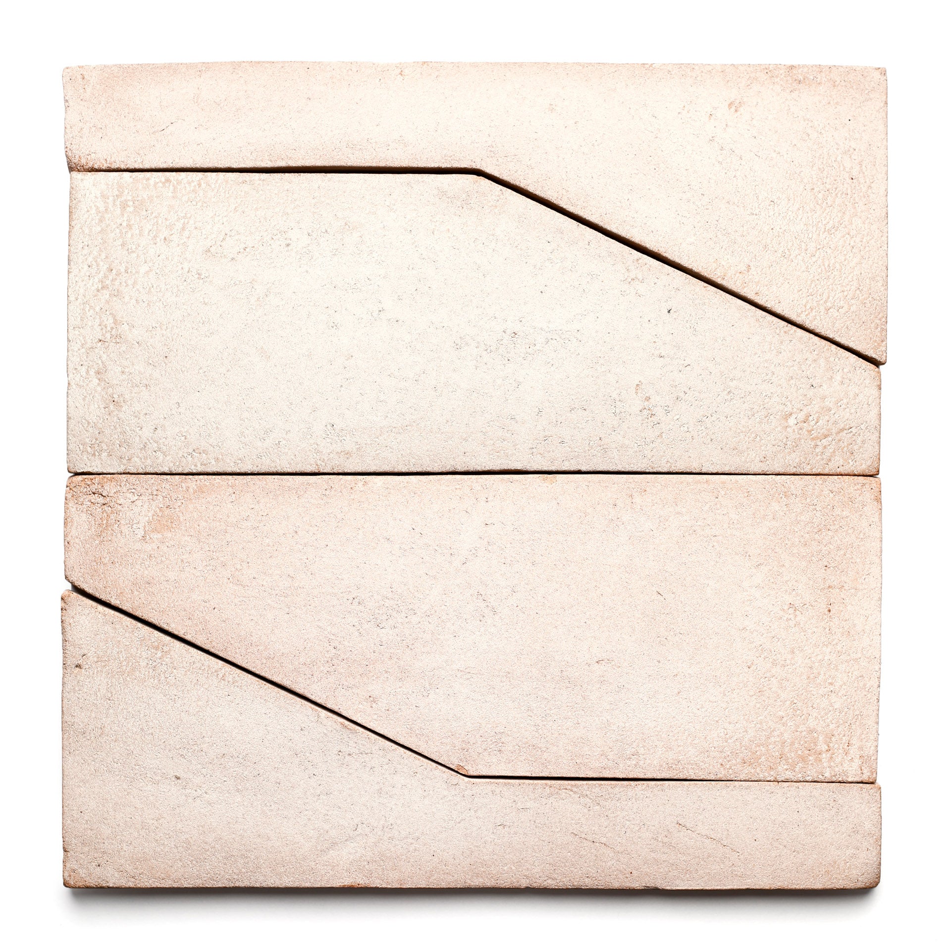 Four Zia Tile "Zocalo + Blanco" rectangular cream tiles are arranged in a square, each featuring a diagonal groove that forms geometric patterns where they meet, all set against a white background.