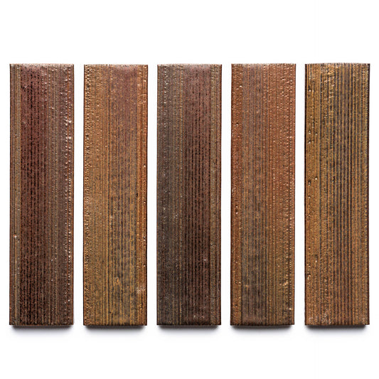 Buckeye + Etched by Zia Tile features five rectangular panels in brown and copper, each with vertical grooves and a metallic sheen, displayed side by side against a white background.