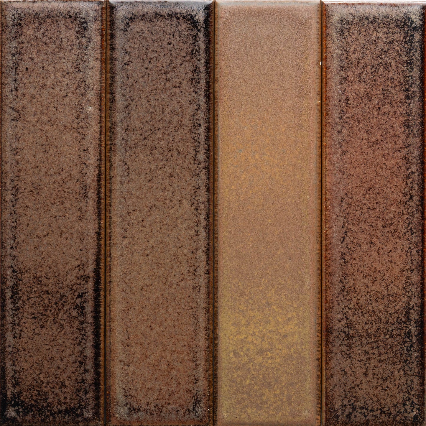 Buckeye + Flat by Zia Tile features four vertical rectangular panels in varying brown shades, from deep to golden brown, all with a speckled, textured surface.