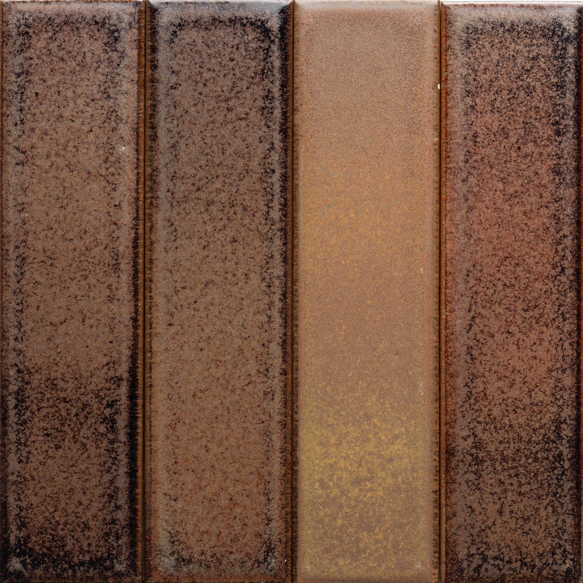 Buckeye + Flat by Zia Tile features four vertical rectangular panels in varying brown shades, from deep to golden brown, all with a speckled, textured surface.