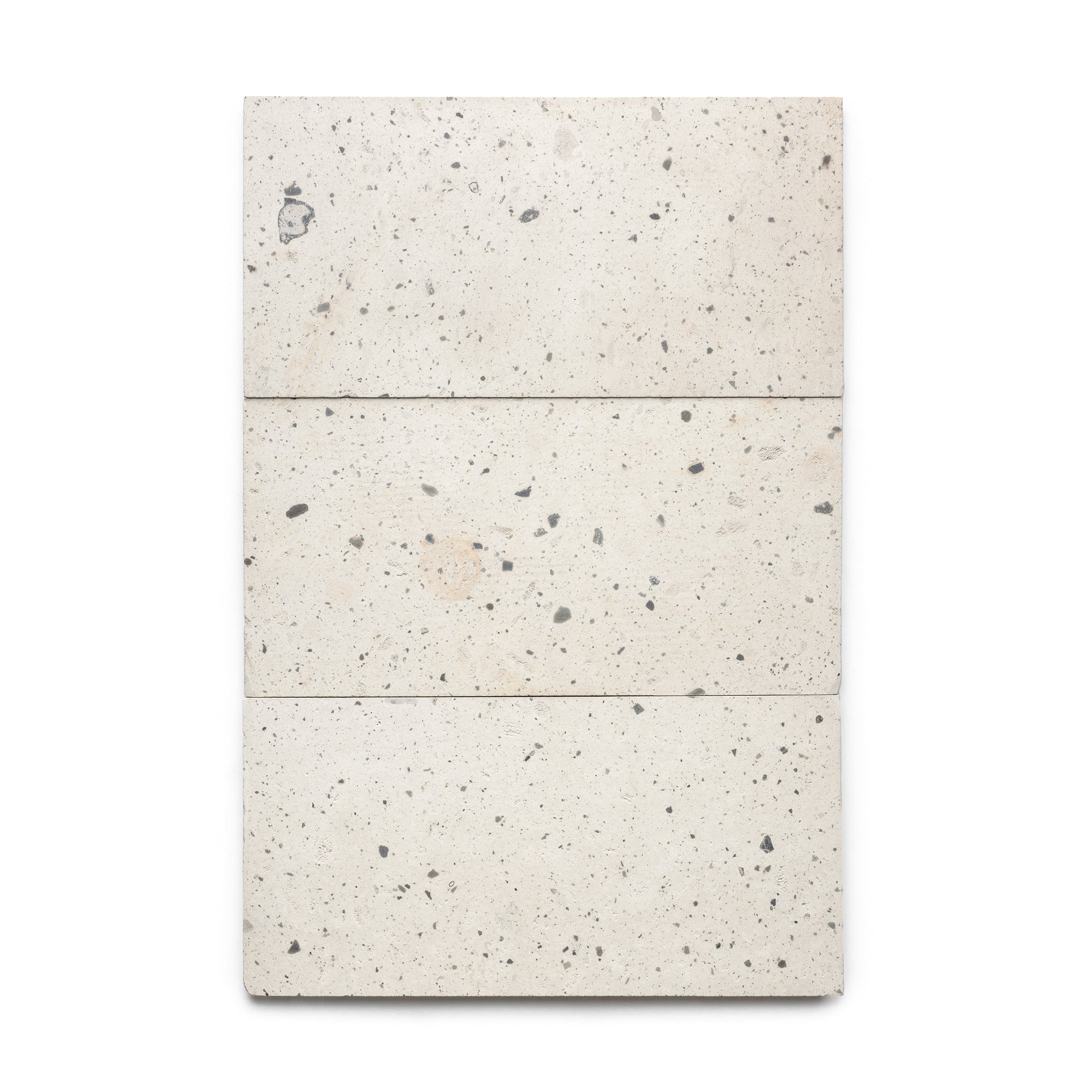 Three Caldera 12x24 tiles by Zia Tile, rectangular and speckled in off-white with gray and beige spots, are arranged vertically to create a neat panel on a plain white background.