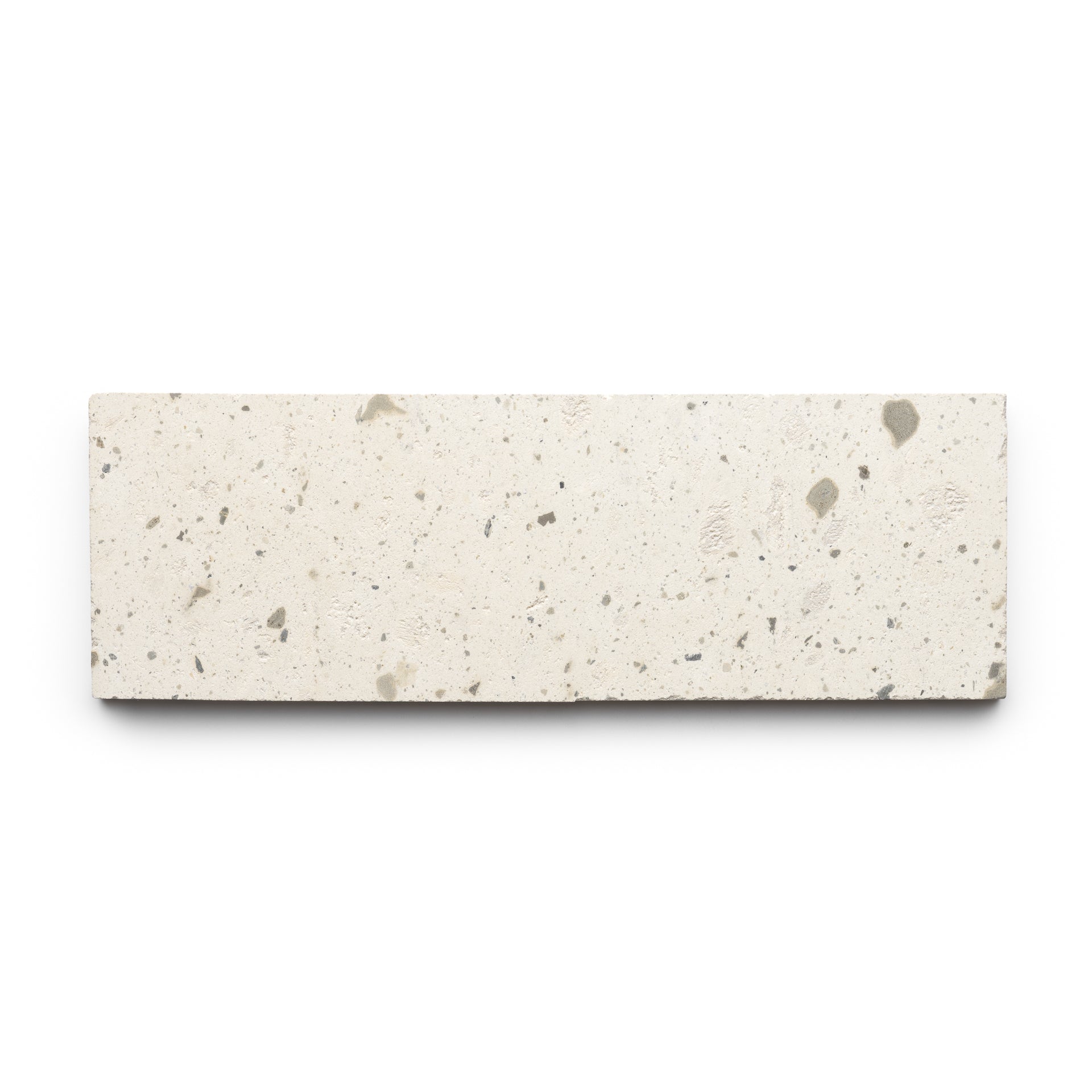 The Zia Tile Caldera 4x12 is a rectangular, off-white tile featuring small gray speckles and a rough, textured surface, shown against a white background.