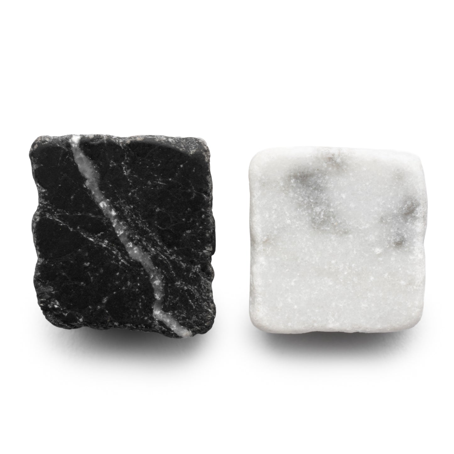 Check in Carrara + Nero Marquina by Zia Tile features two square tiles: one black with white veins and one white with light gray speckles, both with a slightly rough texture and subtly rounded edges.