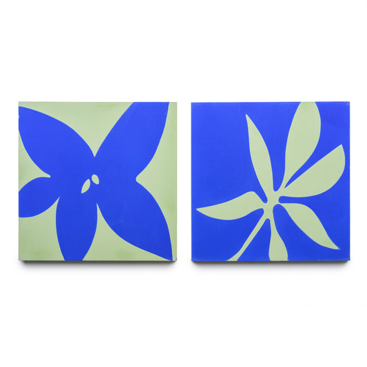 Two Zia Tile Flora 8x8 tiles in Elemental Blue + Nile: each displays abstract blue floral shapes on green. The left tile features a bold four-petal flower; the right shows a five-petal, intricate design.