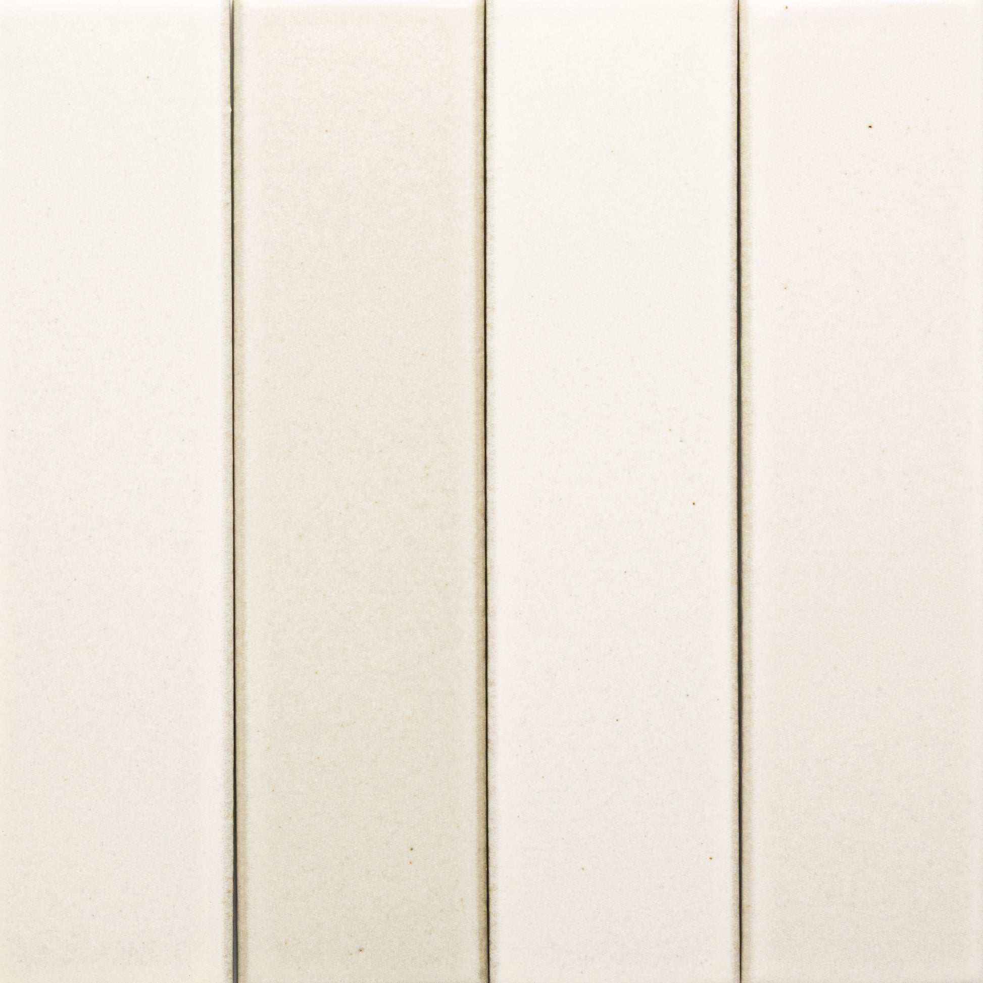 Four vertical, rectangular off-white Feather + Flat ceramic tiles by Zia Tile are arranged side by side, each separated by thin grout lines and featuring subtle color variations.