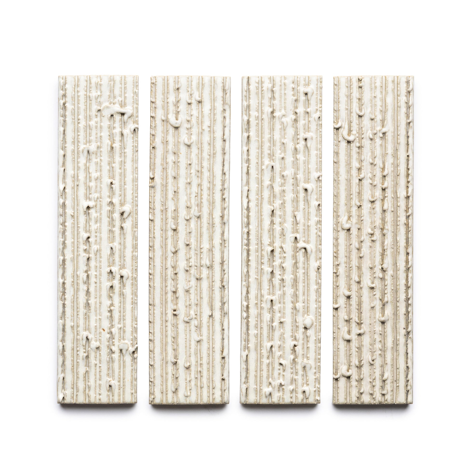 Four rectangular beige Feather + Furrowed tiles by Zia Tile, each with a vertical textured and uneven surface, are arranged side by side on a white background.