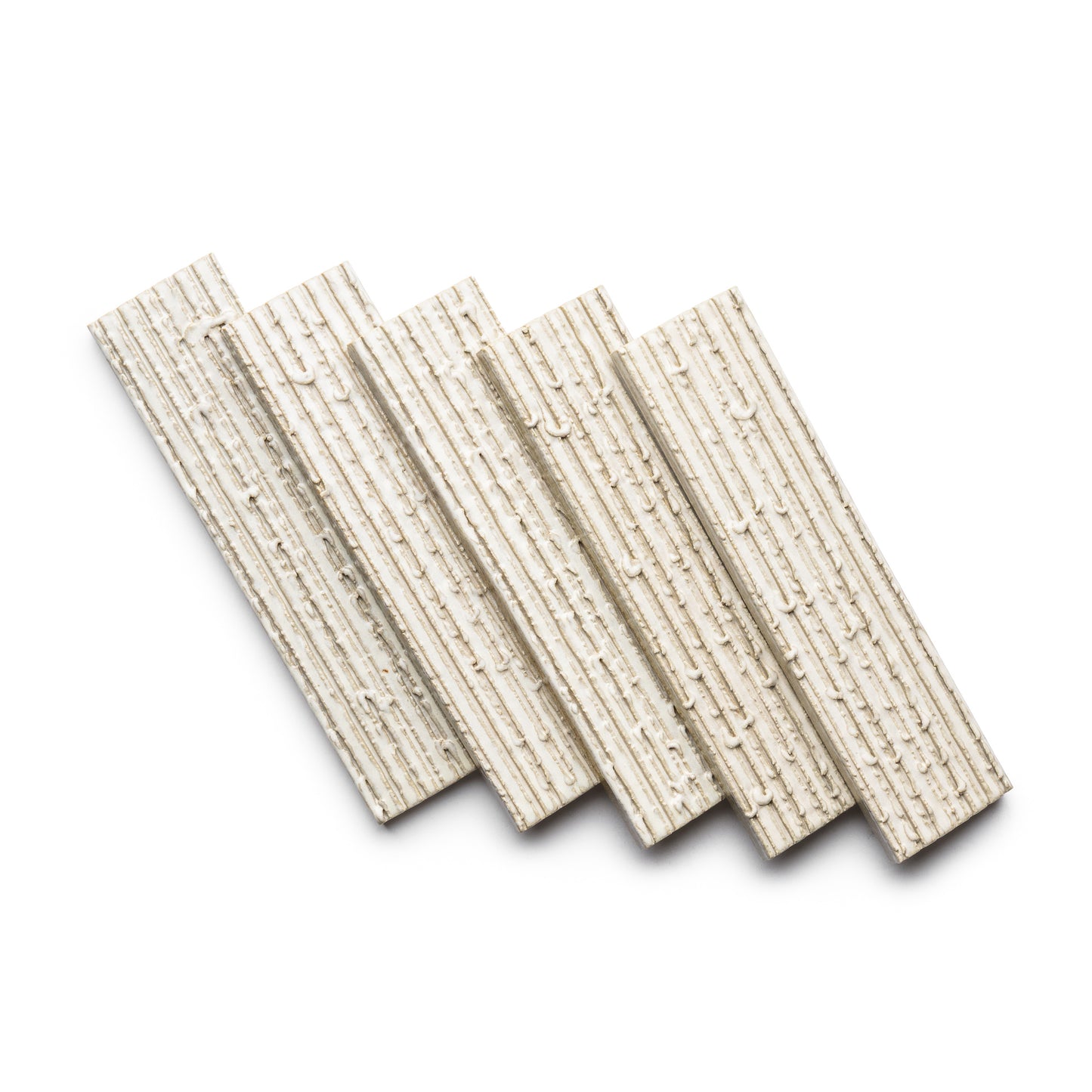 Four Feather + Furrowed tiles by Zia Tile, featuring a ridged texture in off-white, are arranged diagonally in a staggered pattern on a white background.