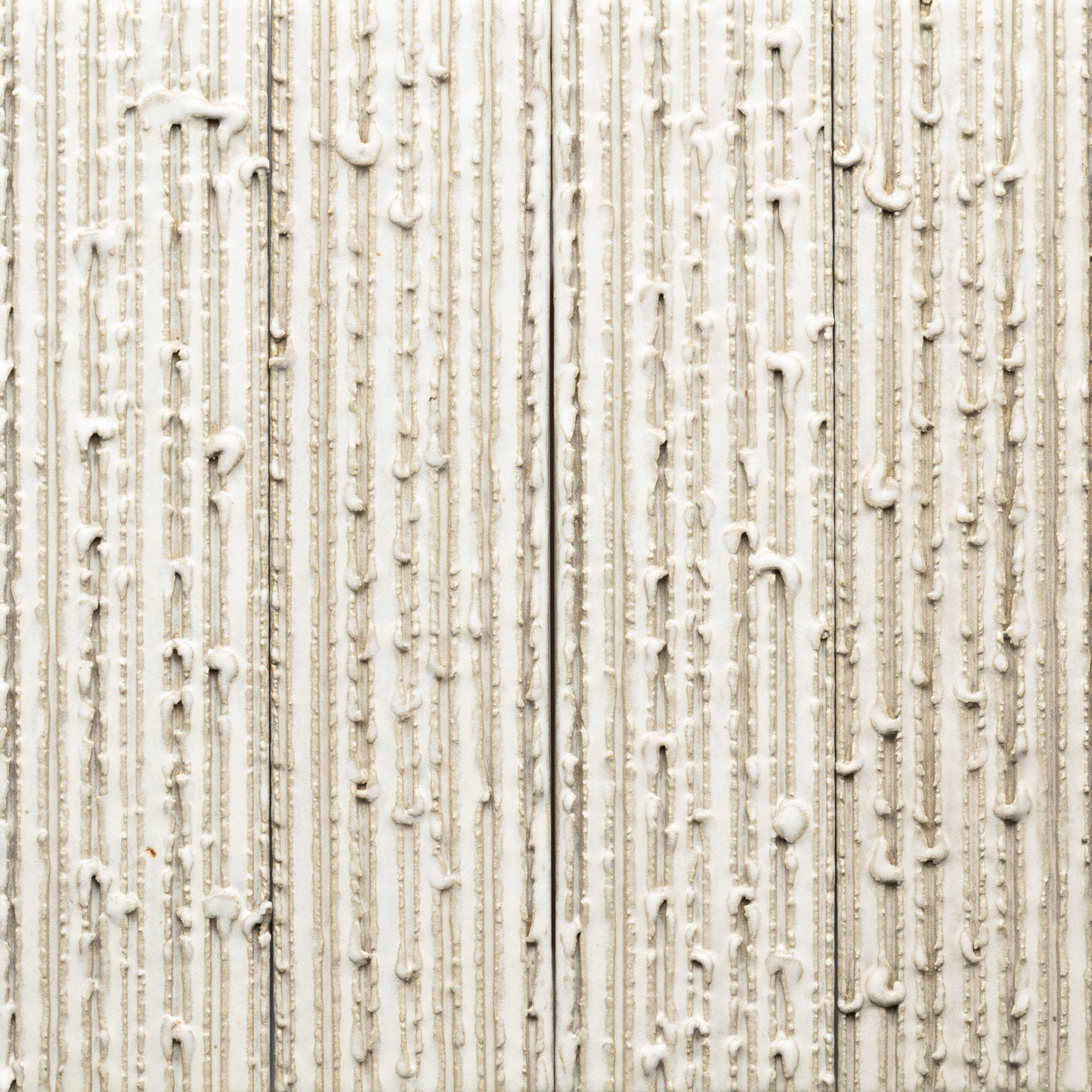 Feather + Furrowed by Zia Tile features a white textured substance dripping down a beige, ribbed surface. The rough, patterned background and irregular lines create an abstract, tactile effect.