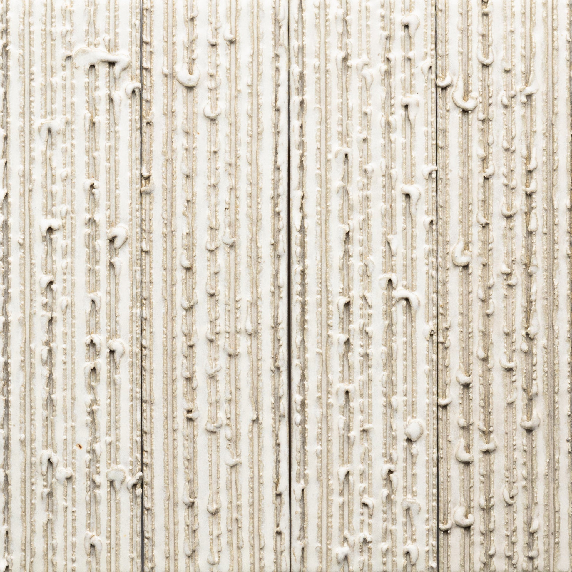 Feather + Furrowed by Zia Tile features a white textured substance dripping down a beige, ribbed surface. The rough, patterned background and irregular lines create an abstract, tactile effect.